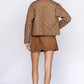 Woman wearing a brown patterned shirt and shorts on a white background